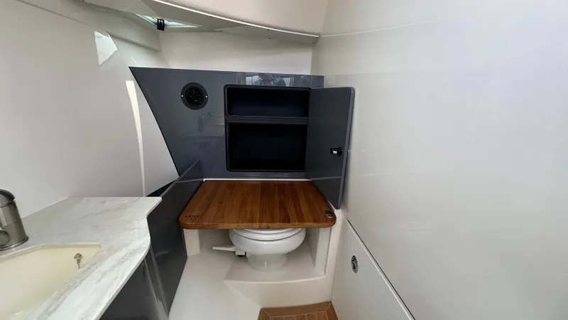 Slide: The Image of 2025 Boston Whaler 330 Vantage boat interior with compact bathroom and wooden accents. - 19