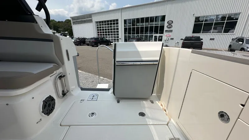 Slide: The Image of 2025 Boston Whaler 330 Vantage boat interior with seating and storage, docked near a building. - 8