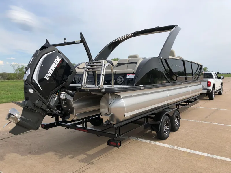 Slide: The Image of 2018 South Bay 25 Sport CR9 pontoon boat on trailer, featuring Evinrude outboard motor. - 13