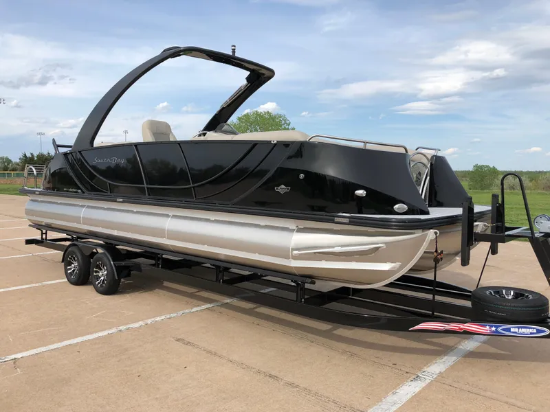 Slide: The Image of 2018 South Bay 25 Sport CR9 pontoon boat on a trailer in a parking lot. - 18