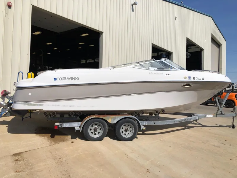 Slide: The Image of 1997 Four Winns 240 Horizon boat on trailer outside a large building. - 1