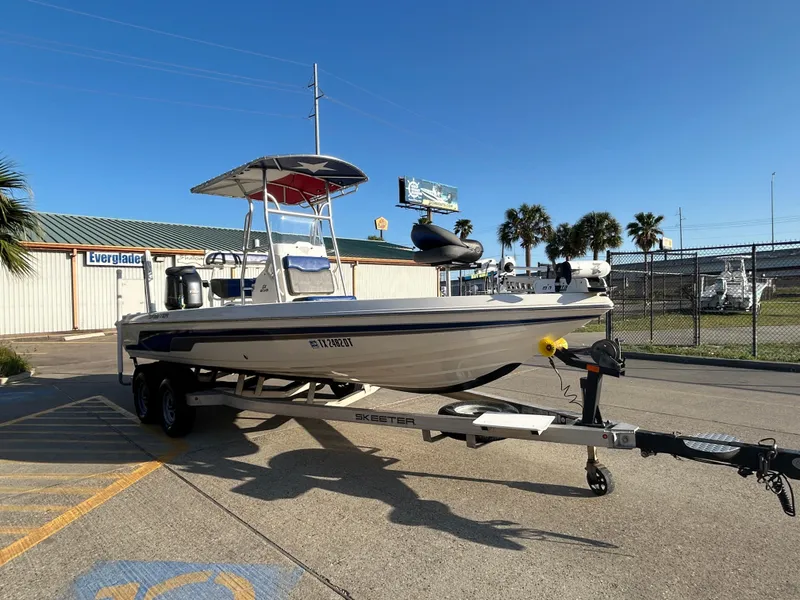 Slide: The Image of 2016 Skeeter SX 210 boat on trailer, parked outdoors under clear blue sky. - 3