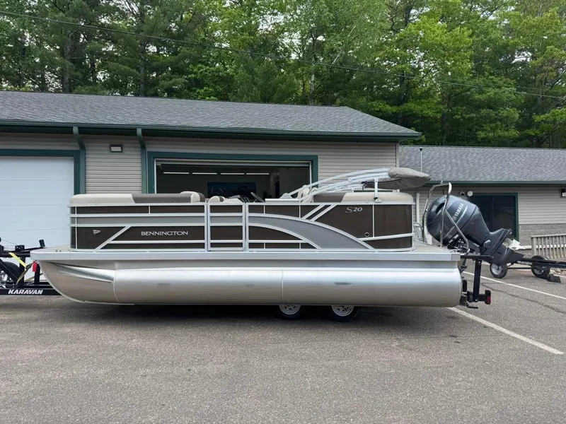 Slide: The Image of 2025 Bennington 20SSR pontoon boat parked outside a garage, featuring sleek design and modern outboard motor. - 1