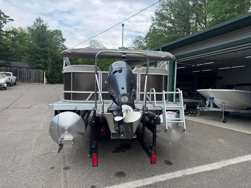 Slide: The Image of 2025 Bennington 20SSR pontoon boat with outboard motor, parked near a garage. - 5