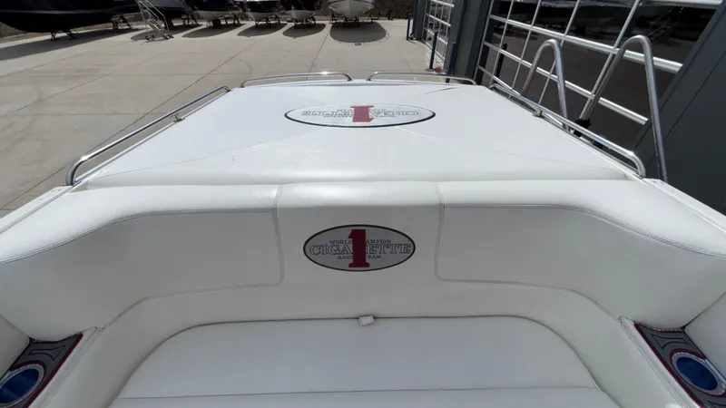 Slide: The Image of 1993 Cigarette 38 Top Gun boat with white seating and logo, docked near a building. - 12