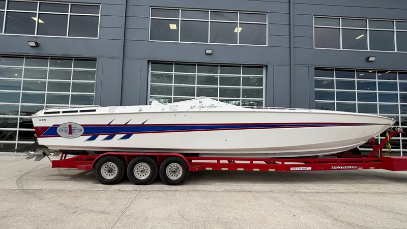 Slide: The Image of 1993 Cigarette 38 Top Gun boat on red trailer, parked in front of a modern building. - 2