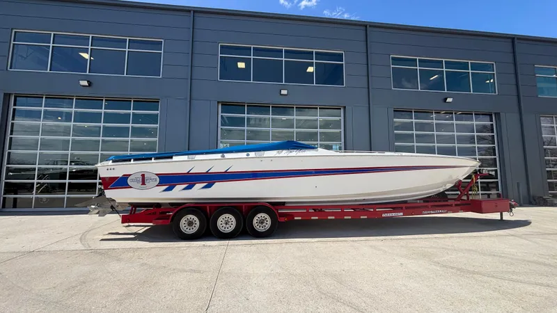 Slide: The Image of 1993 Cigarette 38 Top Gun boat on red trailer, parked outside a modern building. - 8