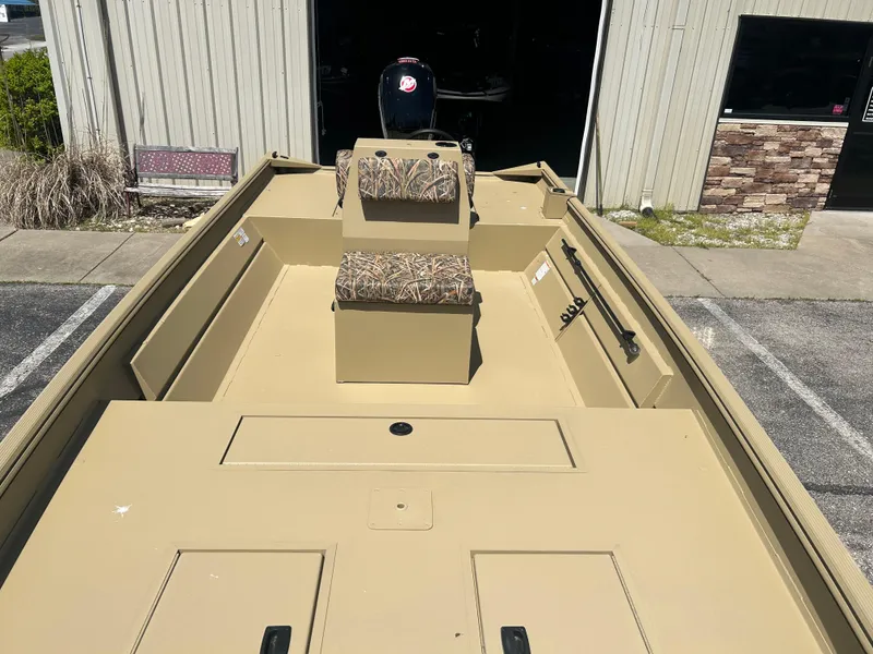 Slide: The Image of 2025 Lowe Roughneck 2070 CC boat with camouflage seating, parked outside a building. - 6