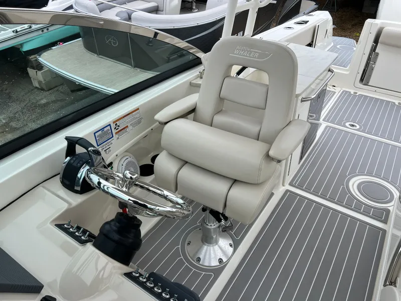 Slide: The Image of 2018 Boston Whaler 270 Vantage boat helm with cushioned captain's chair and steering wheel. - 25