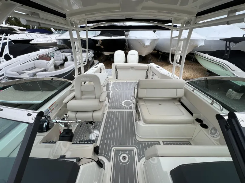 Slide: The Image of 2018 Boston Whaler 270 Vantage boat interior with seating and helm, docked among other boats. - 28