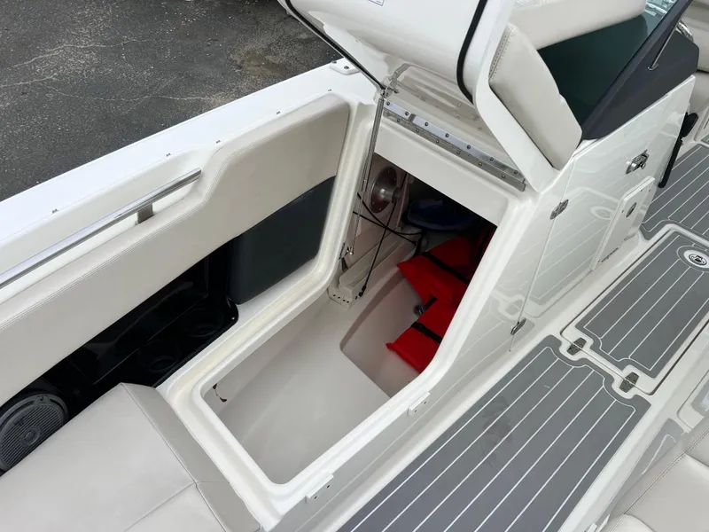 Slide: The Image of 2018 Boston Whaler 270 Vantage boat storage compartment with open hatch and visible life jackets. - 32