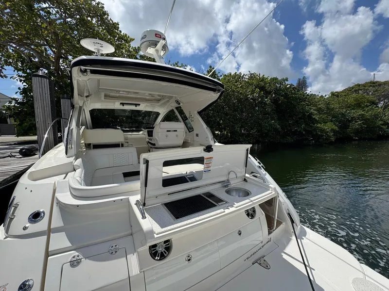 Slide: The Image of 2019 Sea Ray Sundancer 350 Coupe docked, featuring outdoor kitchen and seating area. - 1