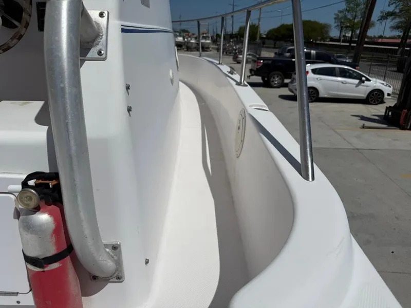Slide: The Image of 2000 Pro-Line 27 Walk boat deck with railing and fire extinguisher, parked in a lot. - 14