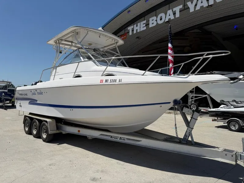 The Image of 2000 Pro-Line 27 Walk boat on trailer outside a yacht facility. - 2