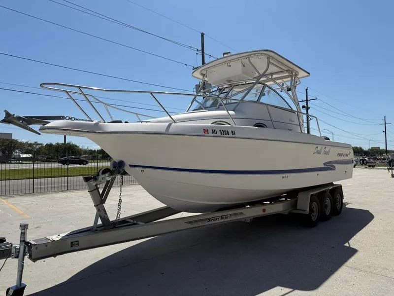 Slide: The Image of 2000 Pro-Line 27 Walk boat on trailer, parked outdoors under clear sky. - 6