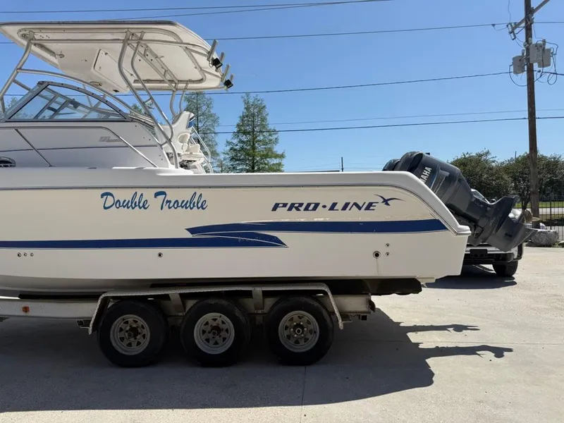 Slide: The Image of 2000 Pro-Line 27 Walk boat on trailer, labeled "Double Trouble," parked outdoors. - 7