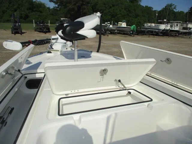 Slide: The Image of 2025 Skeeter SX241 boat with open storage compartments and trolling motor, parked outdoors. - 10