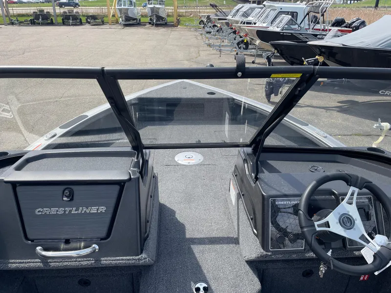 Slide: The Image of 2025 Crestliner 1750 Fish Hawk boat interior with steering wheel and dashboard, parked in a marina. - 14
