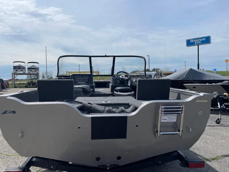 Slide: The Image of 2025 Crestliner 1750 Fish Hawk boat, rear view, parked outdoors under a cloudy sky. - 2