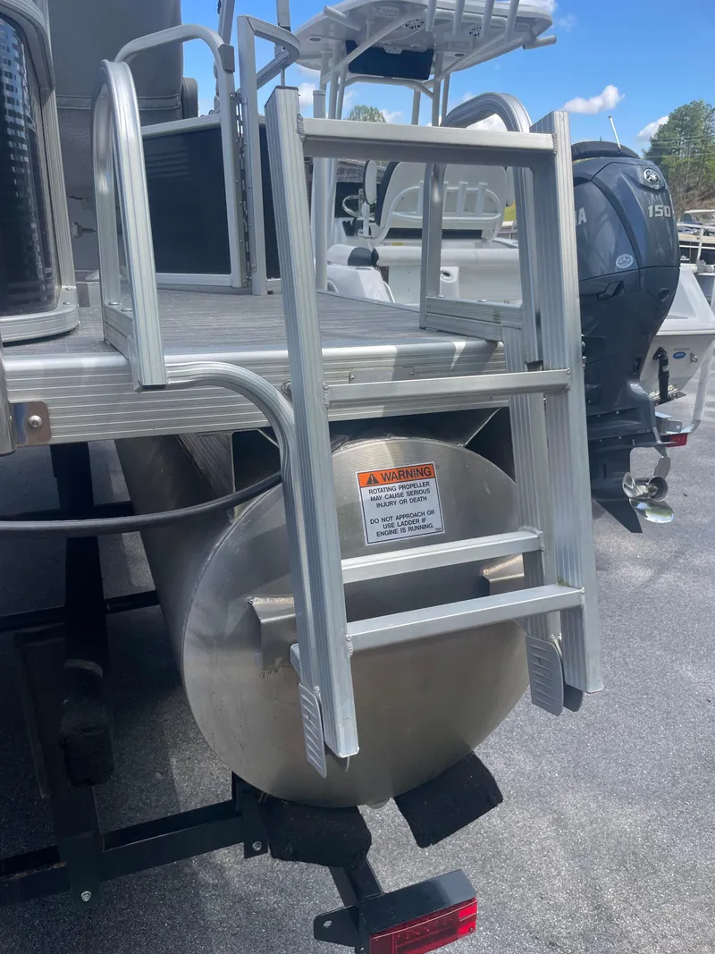 Slide: The Image of 2023 Bennington 20SV boat with aluminum ladder and outboard motor, docked under clear sky. - 3