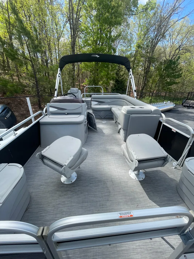 Slide: The Image of 2023 Bennington 20SV pontoon boat with spacious seating, set against a lush, green forest backdrop. - 5