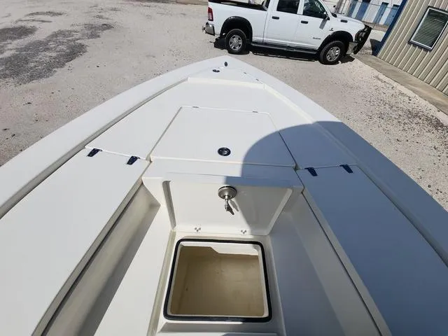 Slide: The Image of 2025 Pathfinder 2300 HPS boat deck with storage compartments, parked near a white truck. - 26