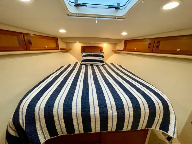 Slide: The Image of Cozy cabin interior of 2006 Cabo 40 Flybridge with striped bedding and overhead lighting. - 14