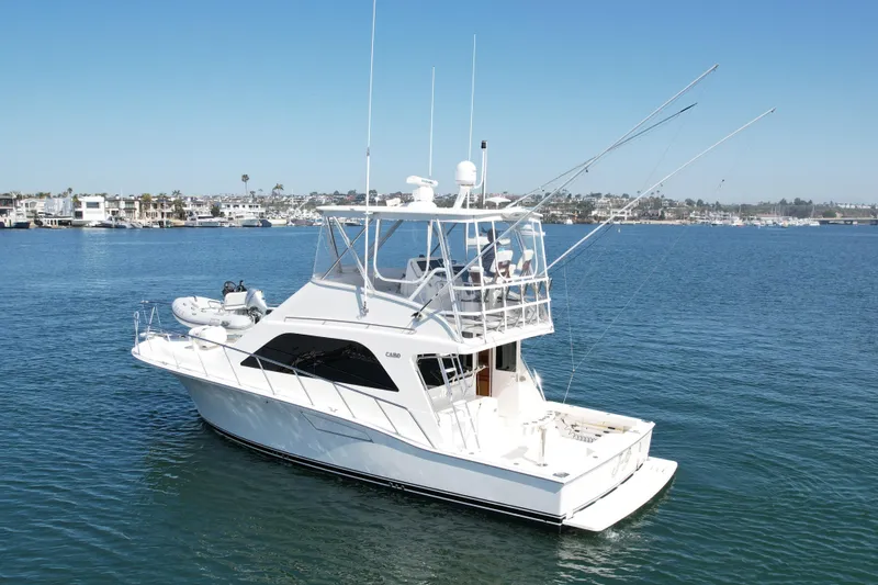 Slide: The Image of 2006 Cabo 40 Flybridge yacht on calm water, clear sky, coastal background. - 4