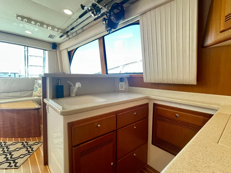 Slide: The Image of 2006 Cabo 40 Flybridge interior with wooden cabinets and countertop in a well-lit cabin. - 45