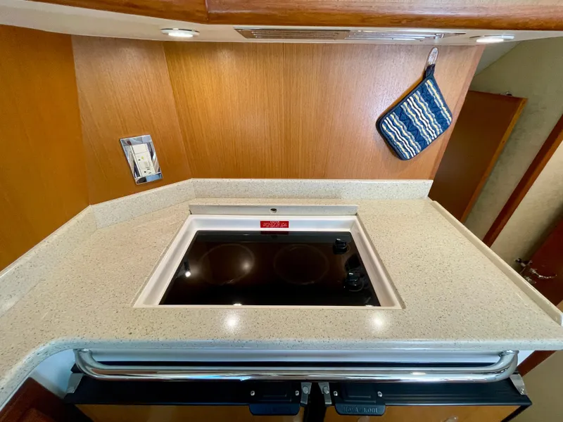 Slide: The Image of 2006 Cabo 40 Flybridge kitchen with stovetop and wooden cabinetry. - 46