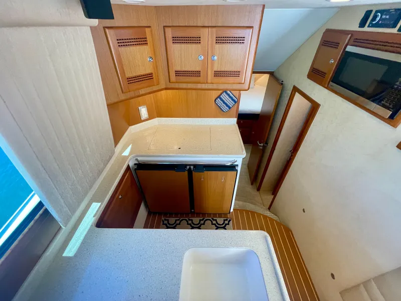 Slide: The Image of Interior of 2006 Cabo 40 Flybridge yacht, featuring kitchen area with wood cabinetry. - 47