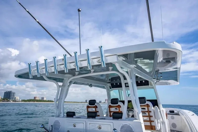 Slide: The Image of 2019 HCB 53 Sueños boat with fishing rod holders, ocean backdrop, and clear sky. - 15