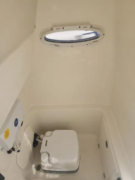 Slide: The Image of 2025 Pathfinder 2400 Open boat interior with compact marine toilet and porthole window. - 20