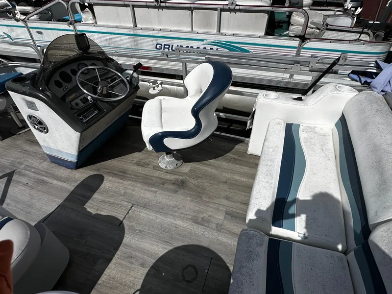 Slide: The Image of 1994 Sylvan Adventure boat interior with steering console, swivel chair, and cushioned seating. - 12