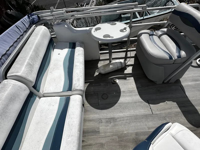 Slide: The Image of 1994 Sylvan Adventure boat interior with striped seating and round table on wooden deck. - 13