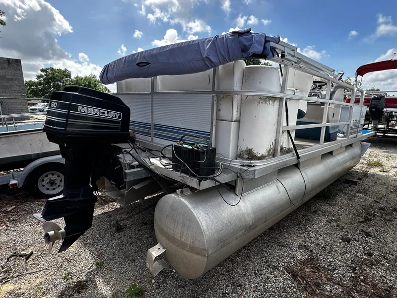Slide: The Image of 1994 Sylvan Adventure pontoon boat with Mercury outboard motor on gravel lot. - 3