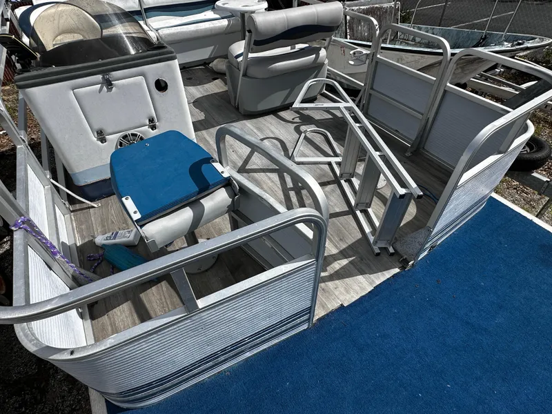 Slide: The Image of 1994 Sylvan Adventure boat interior with blue seating and deck, featuring metal railings. - 7