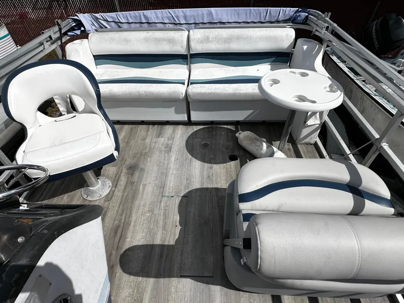 Slide: The Image of 1994 Sylvan Adventure boat interior with white seating, table, and wood flooring. - 8