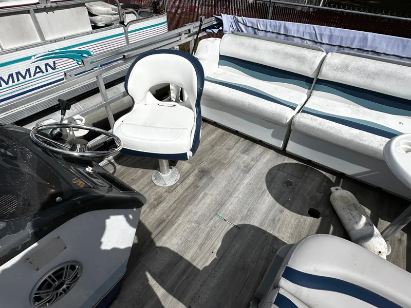 Slide: The Image of 1994 Sylvan Adventure boat interior with white seating and steering wheel on wooden deck. - 9