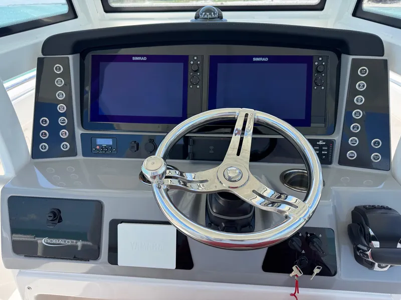 Slide: The Image of 2022 Robalo R272 Center Console dashboard with dual Simrad displays and steering wheel. - 2