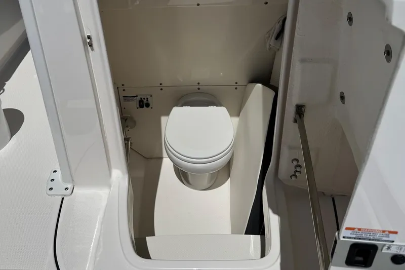 Slide: The Image of 2022 Robalo R272 Center Console boat interior with compact marine toilet. - 8