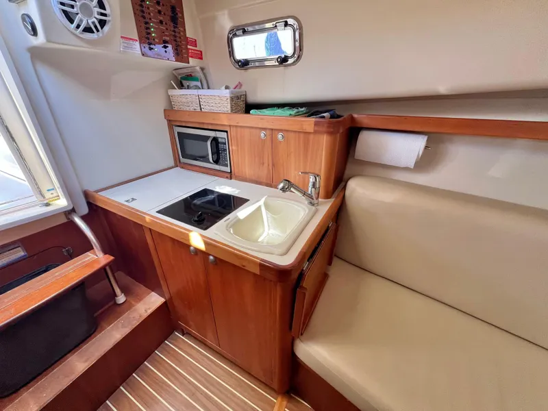 Slide: The Image of 2006 Mainship Pilot 30-II Sedan interior with kitchenette, sink, and seating area. - 16