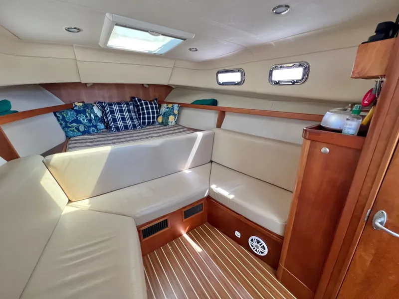 Slide: The Image of 2006 Mainship Pilot 30-II Sedan cabin with beige seating, wood accents, and decorative pillows. - 19