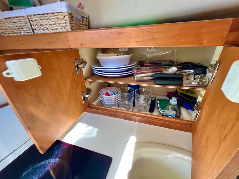 Slide: The Image of Open wooden cabinet in 2006 Mainship Pilot 30-II Sedan, displaying kitchenware and utensils. - 22