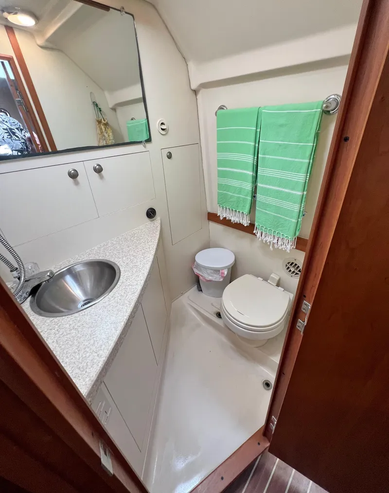 Slide: The Image of 2006 Mainship Pilot 30-II Sedan bathroom with sink, toilet, and green towels. - 24