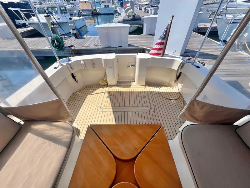 Slide: The Image of 2006 Mainship Pilot 30-II Sedan boat interior with seating, table, and American flag at marina. - 8
