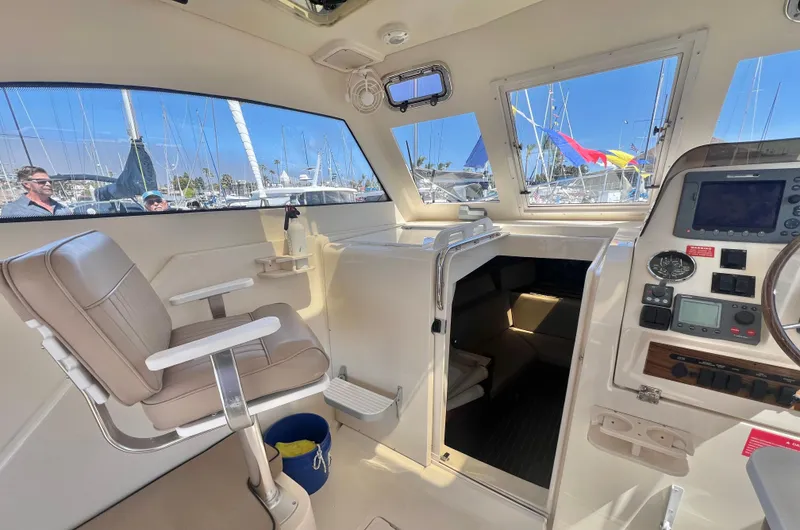 Slide: The Image of 2006 Mainship Pilot 30-II Sedan interior with helm, seating, and marina view. - 9