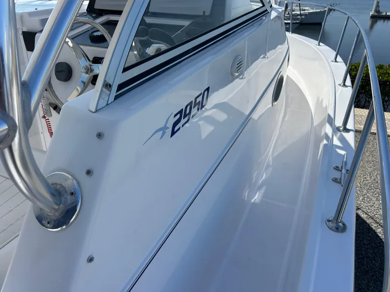 Slide: The Image of 1999 Pro-Line 2950 WALK boat, white exterior, docked, showcasing sleek design and railing. - 12