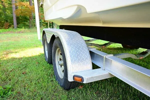 Slide: The Image of Trailer for 2015 Crownline 236 SC boat on grass, featuring dual wheels. - 46