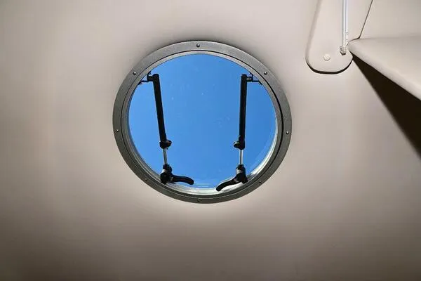 Slide: The Image of Porthole window on 2015 Crownline 236 SC boat, showing clear blue sky. - 29